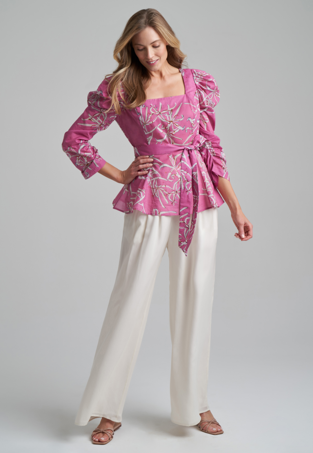 Woman wearing cotton puffed sleeve square neck blouse with belt in watermelon spider lily print by Ala von Auersperg for spring summer 2021