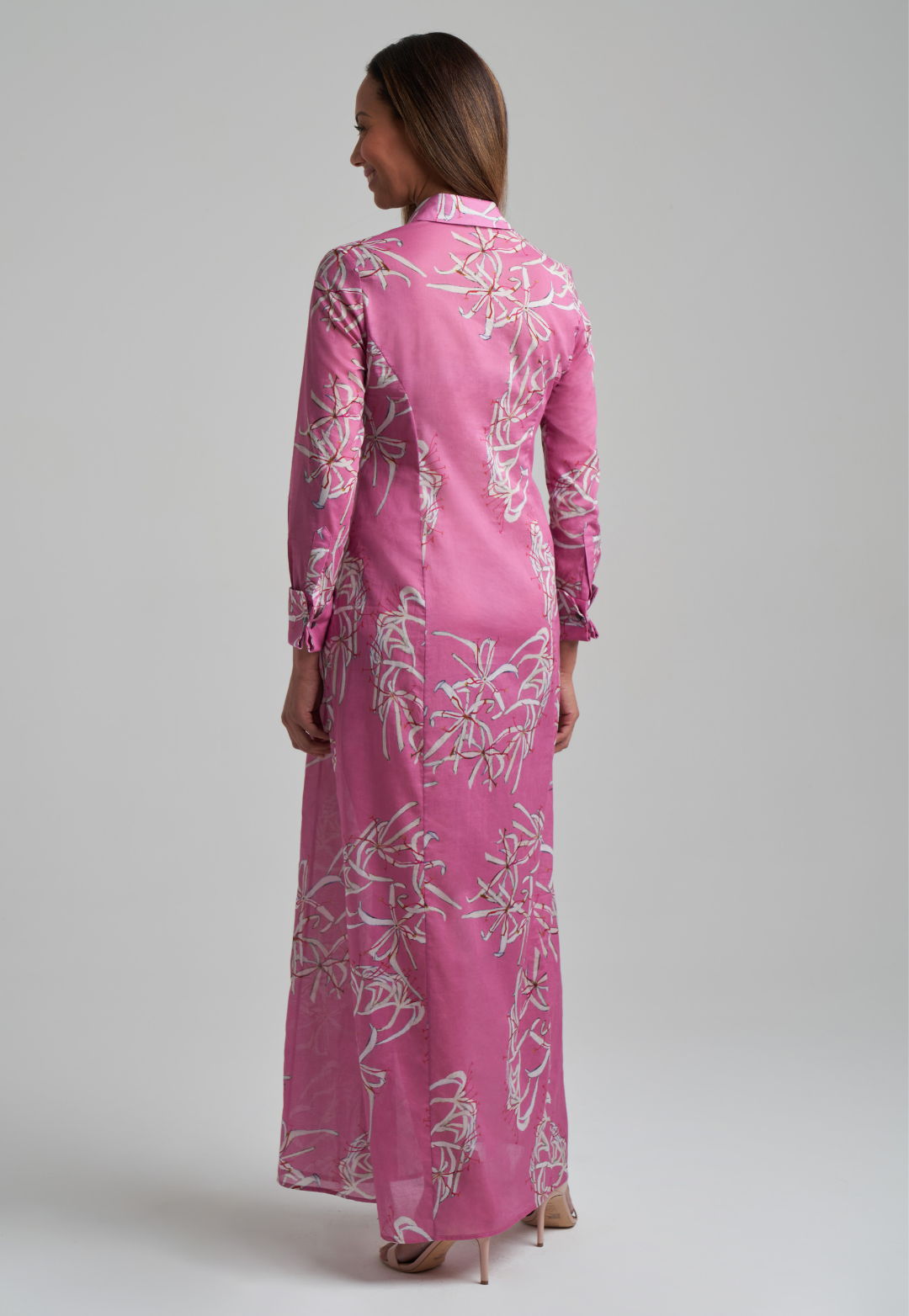 Woman wearing long cotton shirt dress in pink spider lily print by Ala von Auersperg for spring summer 2021