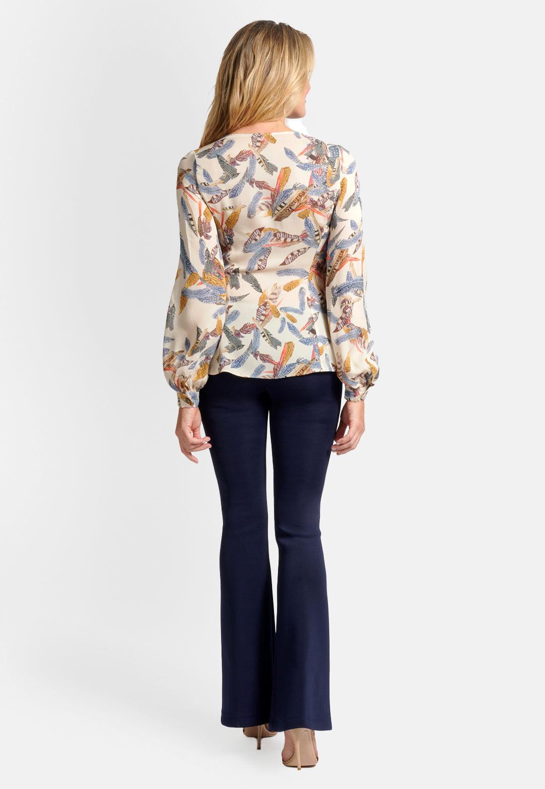 Model wearing cream cowl neck silk blouse top printed with feathers with navy stretch knit pants