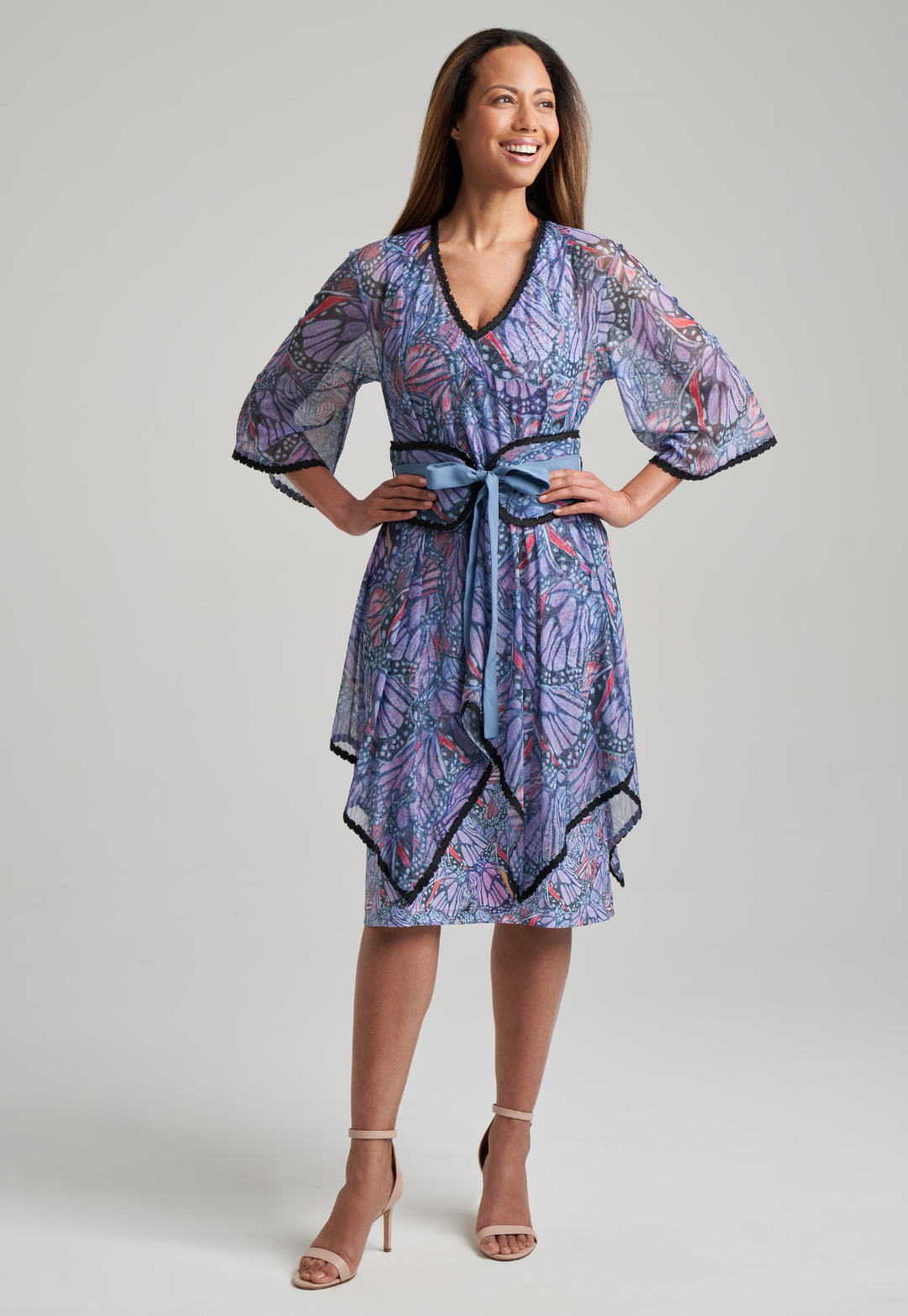 Woman wearing butterfly printed mesh poncho with black trim over printed stretch knit short dress by Ala von Auersperg for spring summer 2021