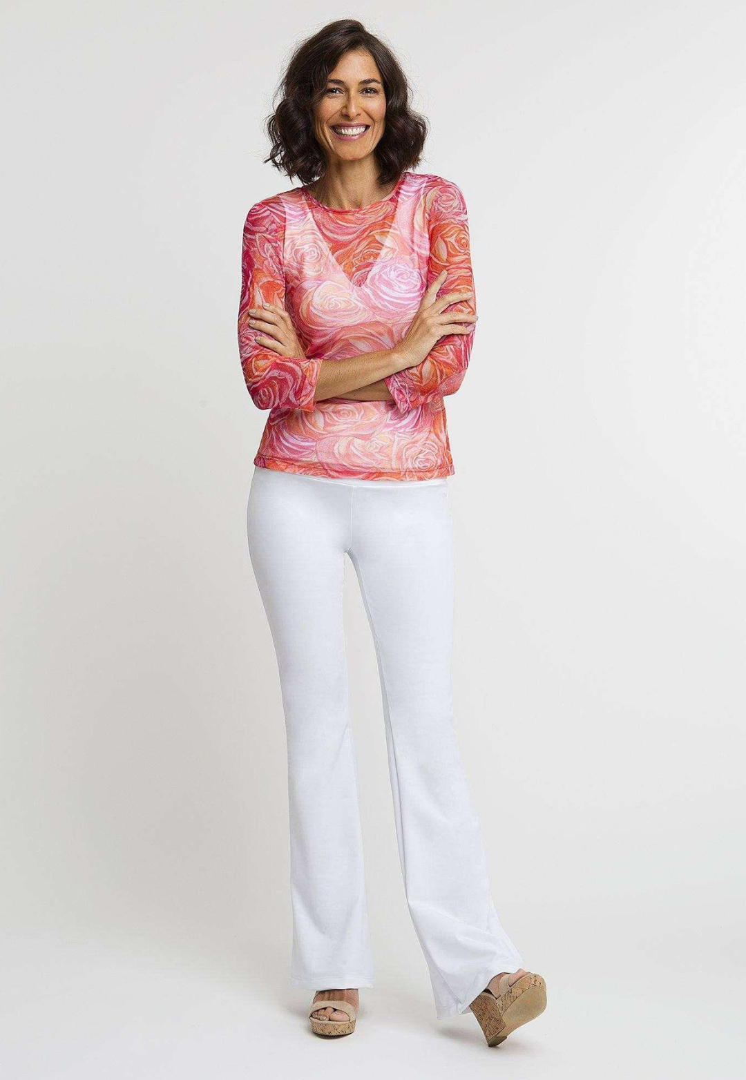Woman wearing mesh pink and orange flower printed shirt over stretch knit white v neck tank top and pants by Ala von Auersperg
