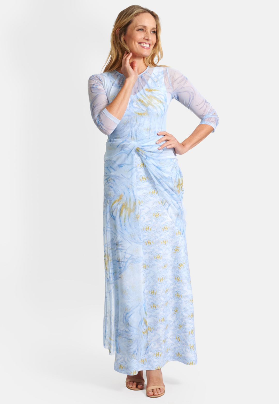 Woman wearing blue and yellow feather printed stretch knit long dress with mesh topper by Ala von Auersperg