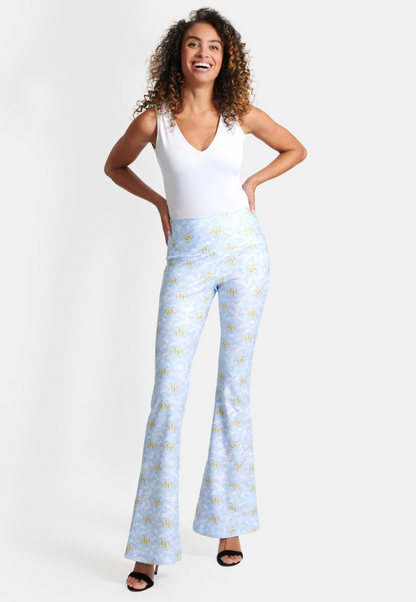 Woman wearing blue and yellow feather printed stretch knit pants with white stretch knit tank top by Ala von Auersperg