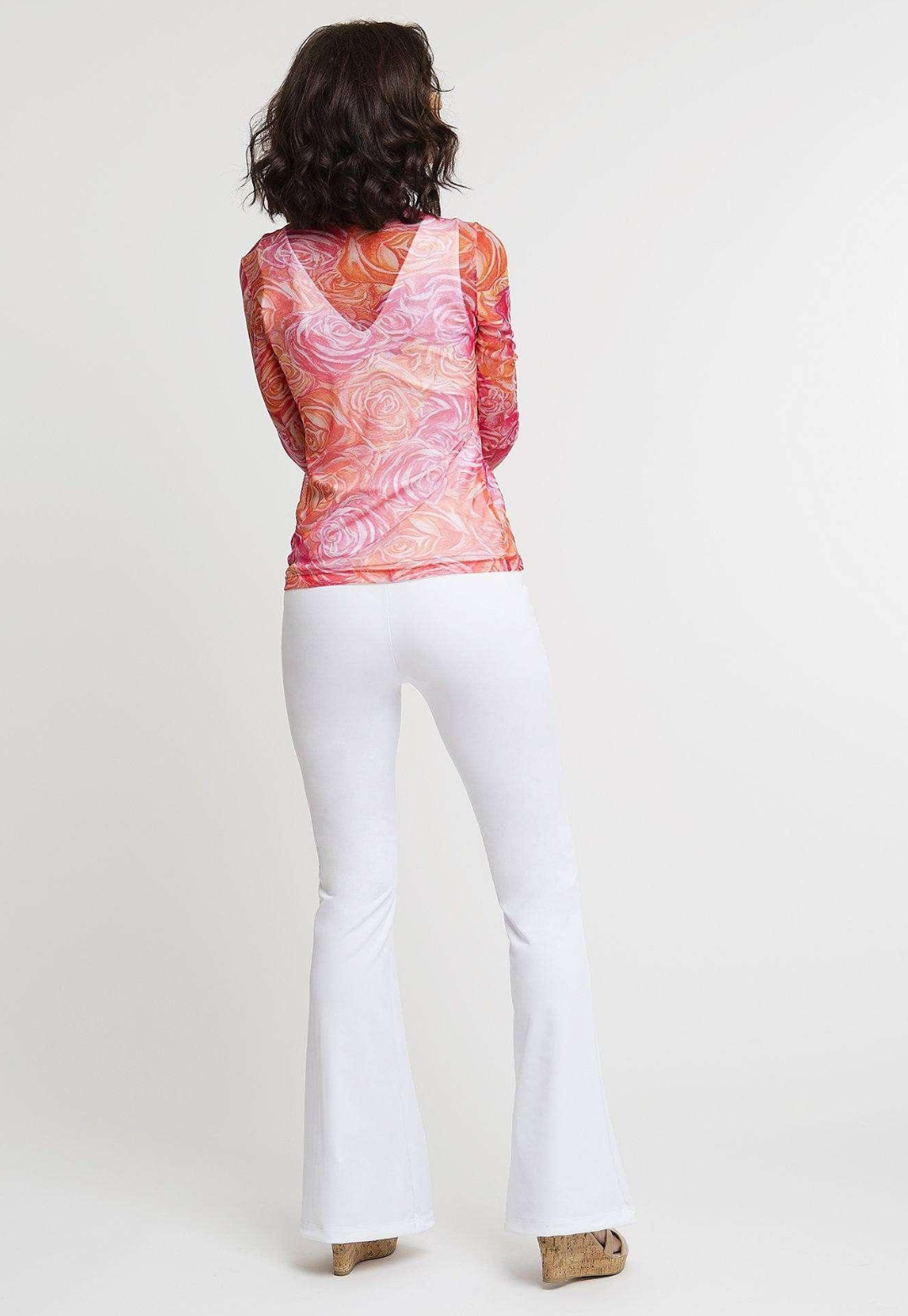 Woman wearing mesh pink and orange flower printed shirt over stretch knit white v neck tank top and pants by Ala von Auersperg