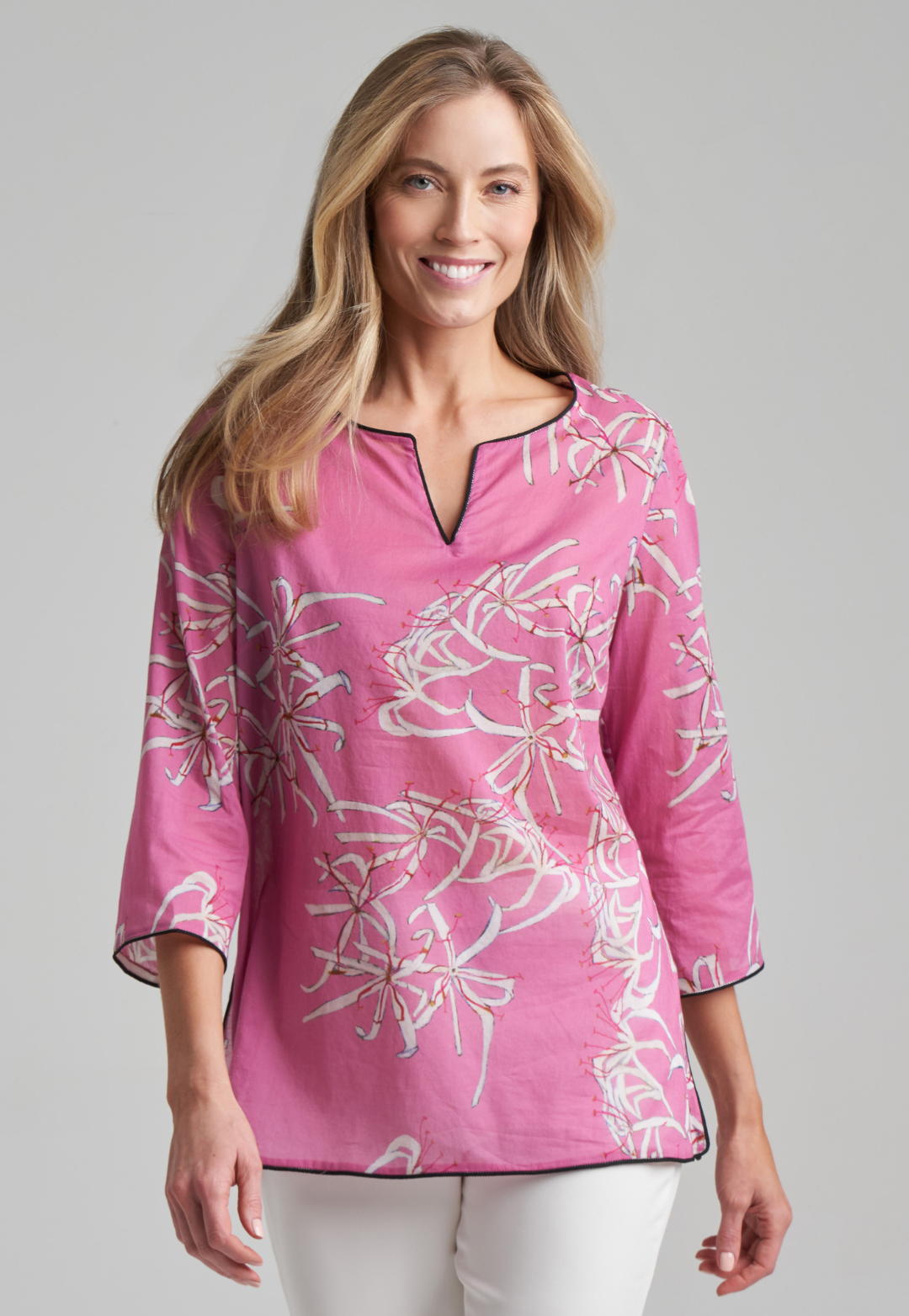 Woman wearing cotton tunic with black piping in watermelon spider lily print by Ala von Auersperg for spring summer 2021